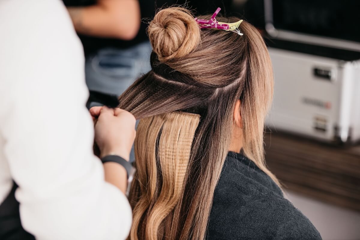 woman getting clip in extensions at the hair salon