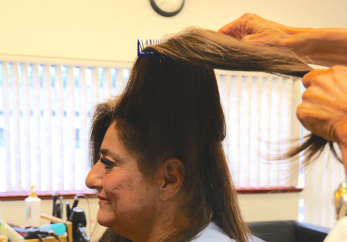 Stylist working with sectioned hair at the roots of a non surgical hair restoration.